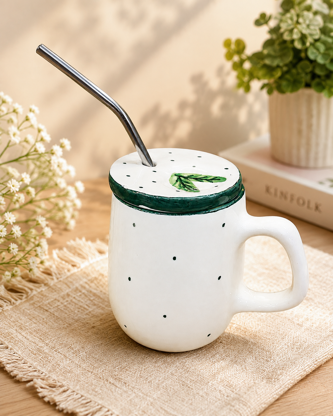 White ceramic mug with green dots, leafy lid and metal straw