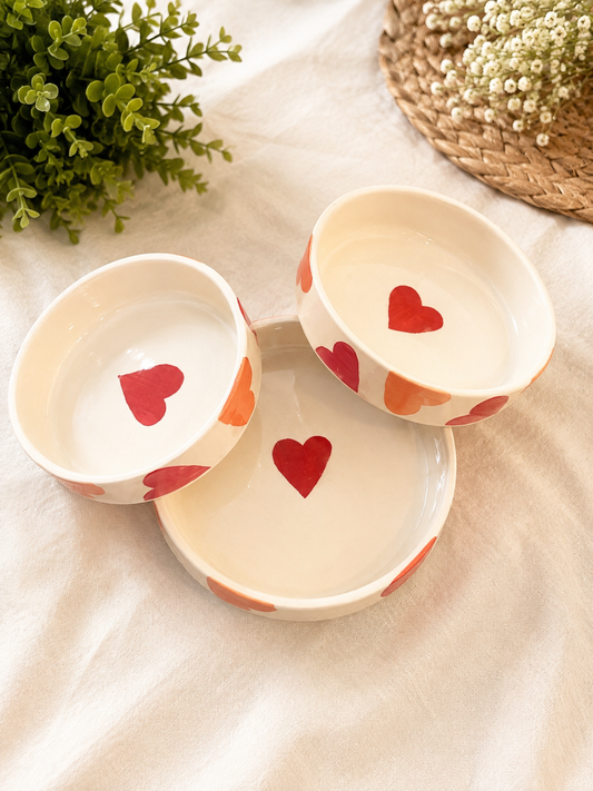 Set of three cream ceramic bowls with red and orange heart designs